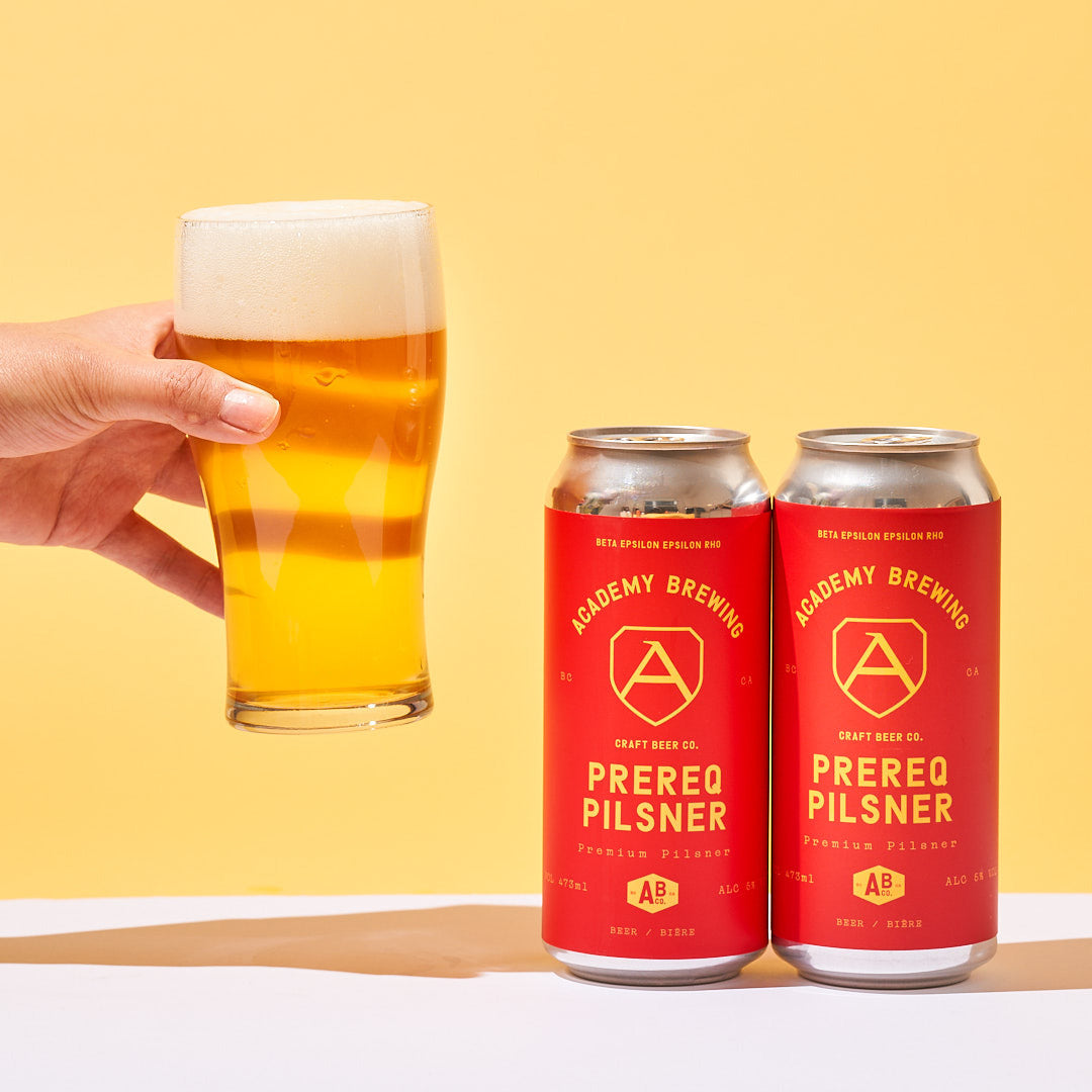 academy brewing prereq pilsner cans with hand holding beer in glass