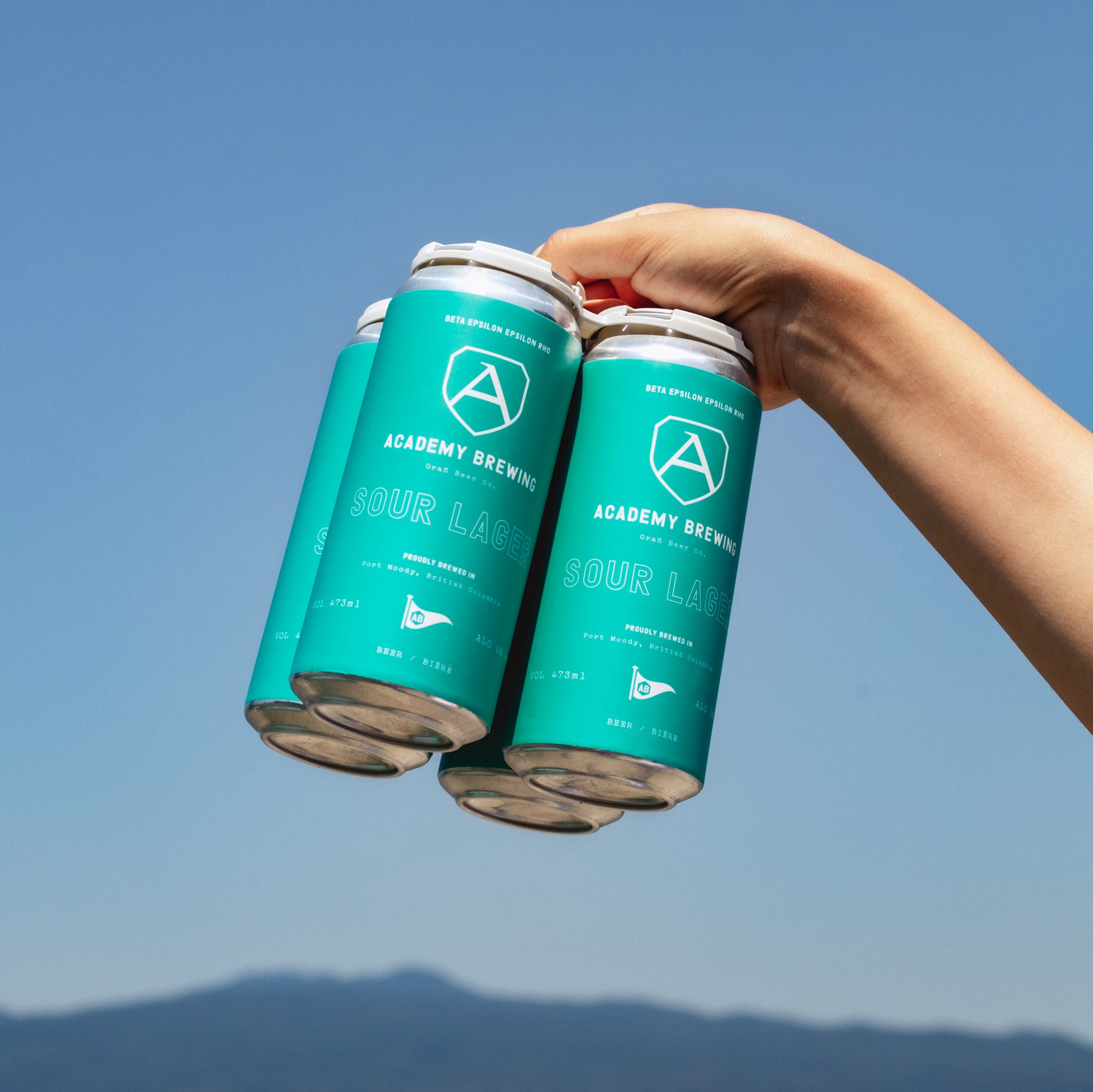 hand holding a pack of academy brewing sour lagers int the sky